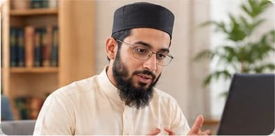 Qari Usman, in glasses, explaining something at a laptop